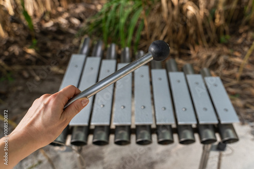 Female hand with mallet and outdoor metal xylophone photo