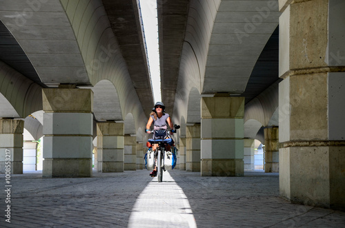 Woman riding alone on a bicycle among beautiful stone pillars and arches under a bridge 