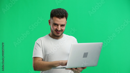 Man, close-up, on a green background, using a laptop