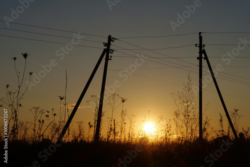 Power lines and beautiful evening sunset in the meadow photo