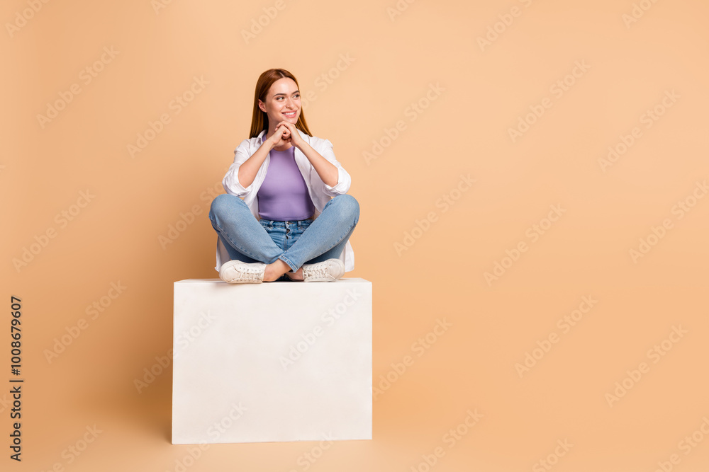 Full length photo of cheerful minded woman dressed cardigan sit on podium look at offer empty space isolated on beige color background Full length photo of cheerful minded woman dressed cardigan sit on podium look at offer empty space isolated on beige color background