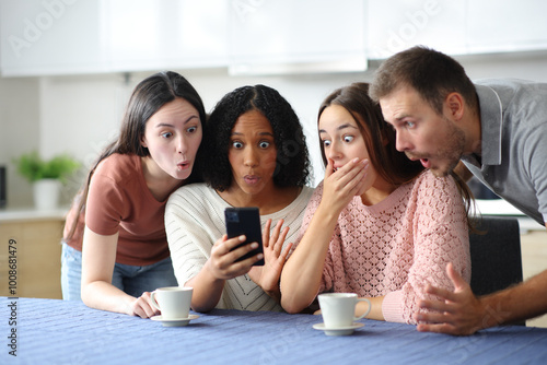 Schilderij op canvas Shocked interracial friends checking phone in the kitchen