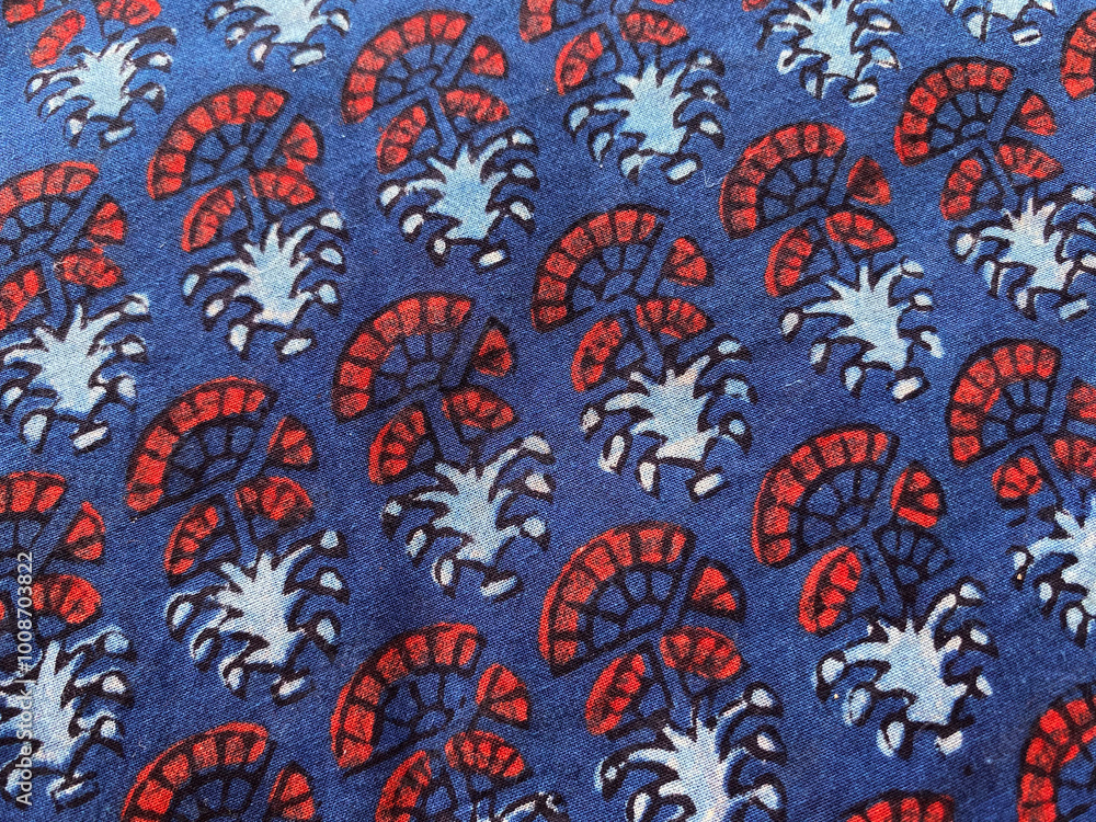 Closeup of red geometric floral block printed fabric on blue cotton fabric Closeup of red geometric floral block printed fabric on blue cotton fabric