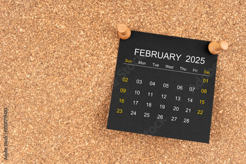 Black calendar sheet for February 2025 with thumbtack on wooden board, Position with copy space.