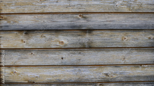 Close-up of a wooden wall consisting of horizontally laid planks. The wood looks weathered and old, with visible fiber patterns, knots and some discoloration due to environmental exposure, giving it a