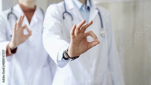 Two doctors is showing ok sign with fingers while standing in a hospital. Teamwork and success in medicine