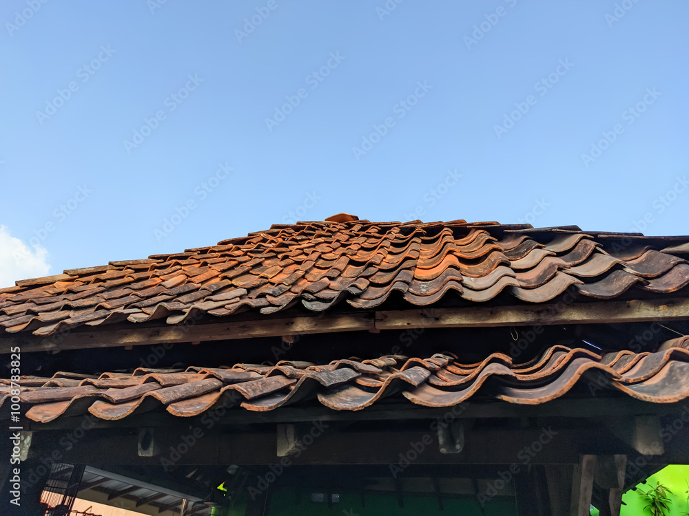 The roof of the building, adorned with traditional old-style tiles, creates a nostalgic scene against the backdrop of a clear blue sky. The roof of the building, adorned with traditional old-style tiles, creates a nostalgic scene against the backdrop of a clear blue sky.