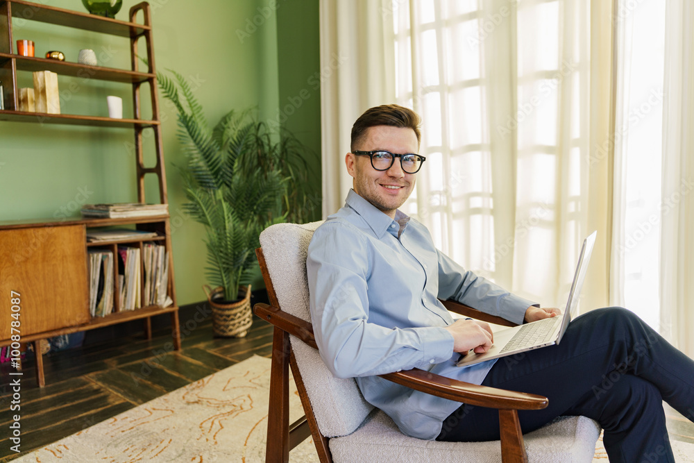 A Young Man Working on a Laptop in a Stylish Living Room With Plants and a Cozy Atmosphere During the Daytime A Young Man Working on a Laptop in a Stylish Living Room With Plants and a Cozy Atmosphere During the Daytime
