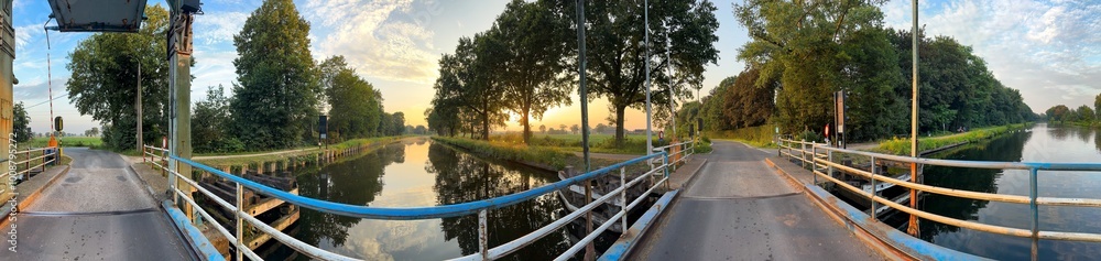 A beautifully picturesque view of a bridge that is surrounded by vibrant trees, reflecting sunset colors in the water A beautifully picturesque view of a bridge that is surrounded by vibrant trees, reflecting sunset colors in the water