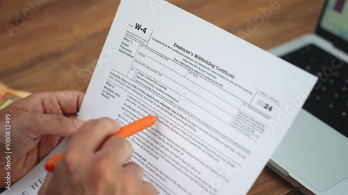 Office worker indicates important information on W-4 tax form with pen reviewing document thoroughly to make informed decisions about tax withholdings slow motion