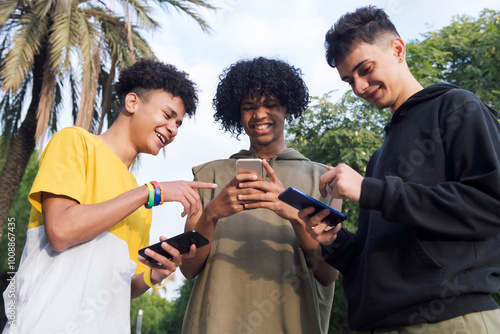 Photography low angle of teen diverse friends having fun surfing Internet on cellphones smil