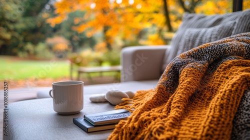 Espacio acogedor en una terraza con una manta tejida, una taza de café y un libro. El paisaje otoñal y la luz suave crean un ambiente perfecto para la relajación.