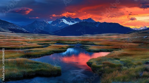  A river runs through a green field beneath pink-orange clouds, framed by mountains