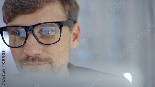 Businessman with glasses looking intently obscured partially by a translucent surface of laptop. Business concept