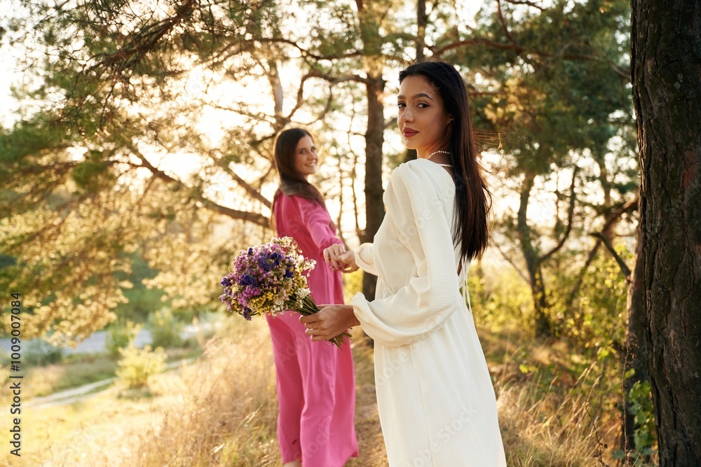 Naklejka premium Woman is want to go, with bouquet of flowers. Lovely lesbian couple are together outdoors in nature