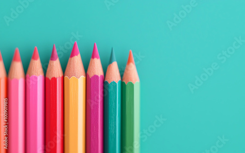 Colorful pencils arranged neatly on a turquoise background, perfect for artistic and creative projects.