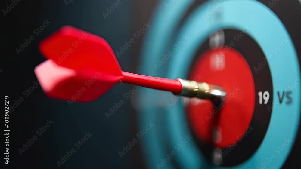 A vibrant red dart is firmly lodged in the bullseye of a blue and black dartboard, symbolizing precision, focus, and achievement in sports and gaming. A vibrant red dart is firmly lodged in the bullseye of a blue and black dartboard, symbolizing precision, focus, and achievement in sports and gaming.