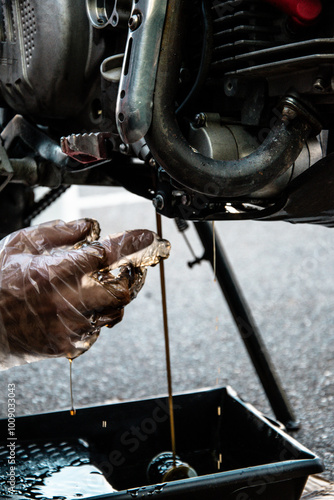 The used engine oil is poured out of the engine into a sump and a hand holds an icy photo