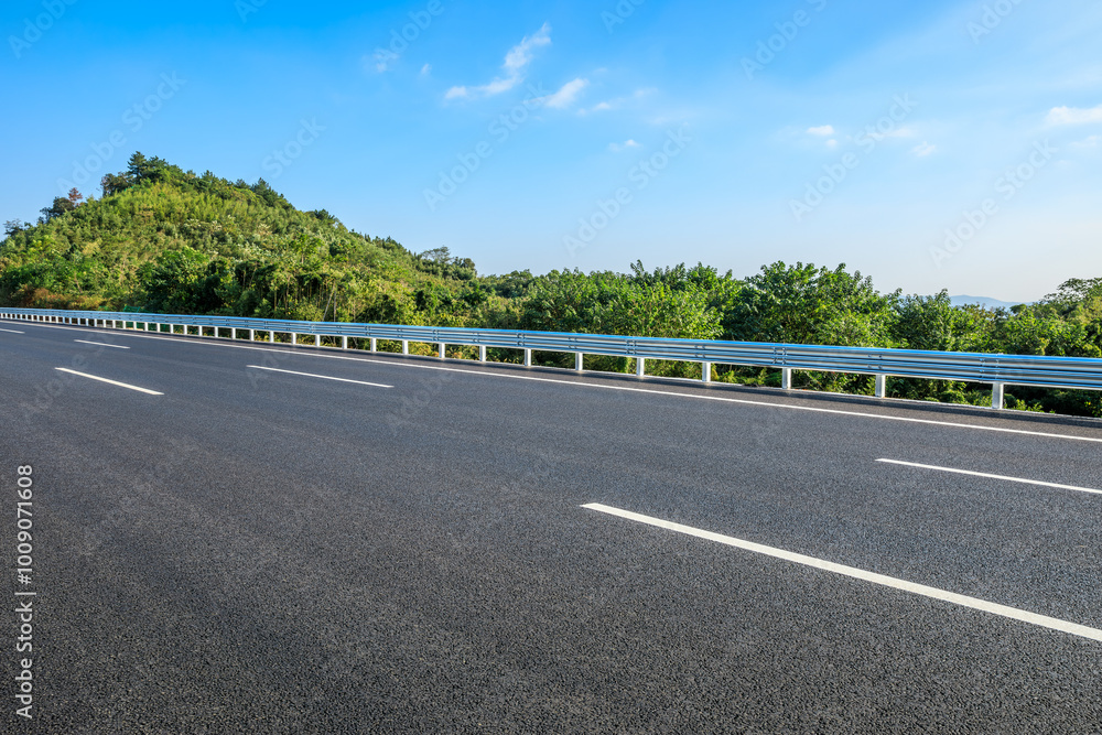 Fototapeta premium Asphalt highway road and green forest nature landscape under blue sky. Car background.