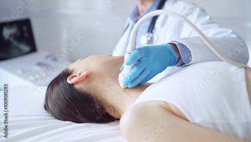 Doctor man wearing blue medical gloves is using ultrasound equipment on neck of female patient lying down for a medical examination