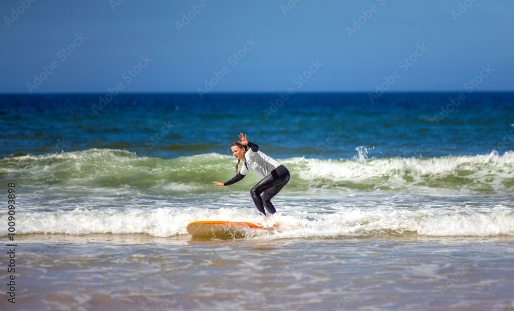 Woman learning to surf on foam in the ocean. First surfing lesson. Amateur surfer. Surfing training. Photo for surfing school advertising on social media. Woman learning to surf on foam in the ocean. First surfing lesson. Amateur surfer. Surfing training. Photo for surfing school advertising on social media.