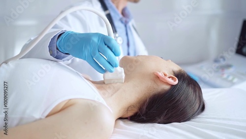 Doctor man wearing blue medical gloves is using ultrasound equipment on neck of female patient lying down for a medical examination