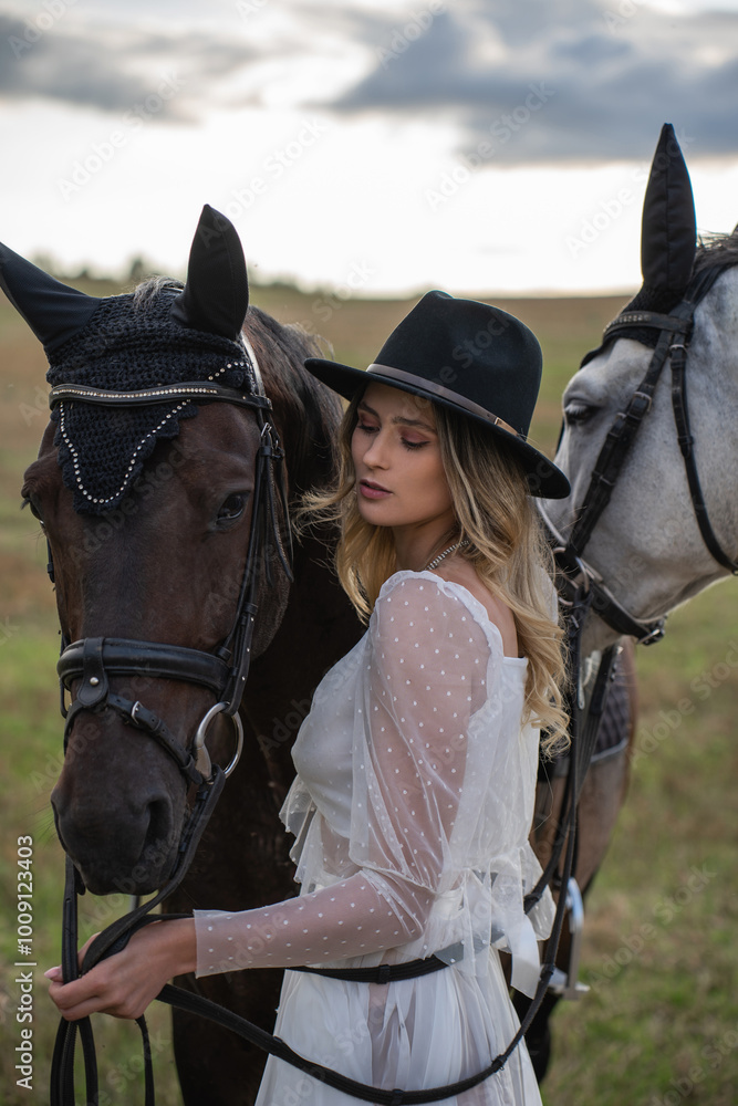 Fototapeta premium Woman in Stylish Outfit with Two Horses in Open Countryside