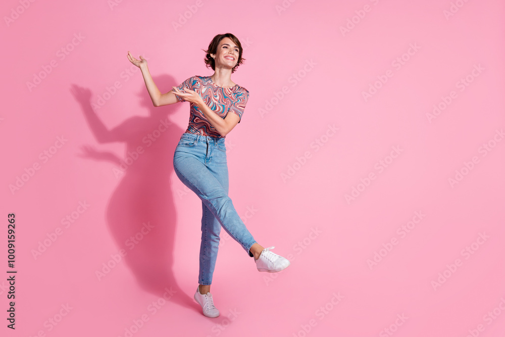 Photo of lovely cute positive girl wear trendy print clothes dance look empty space isolated on pink color background Photo of lovely cute positive girl wear trendy print clothes dance look empty space isolated on pink color background