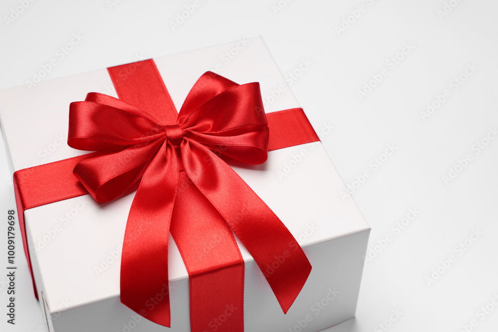 Gift box with red bow on light grey background, closeup Gift box with red bow on light grey background, closeup