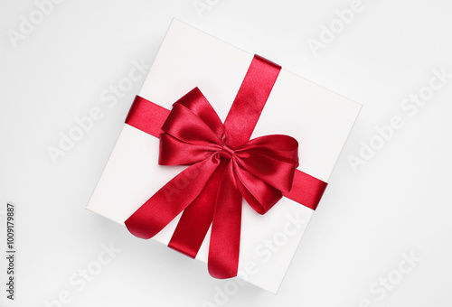 Gift box with red bow on light grey background, top view