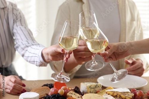 People clinking glasses of wine at served table, closeup