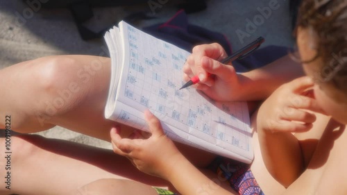 A mum shares and teaches her child arrowwords on the beach, in France photo