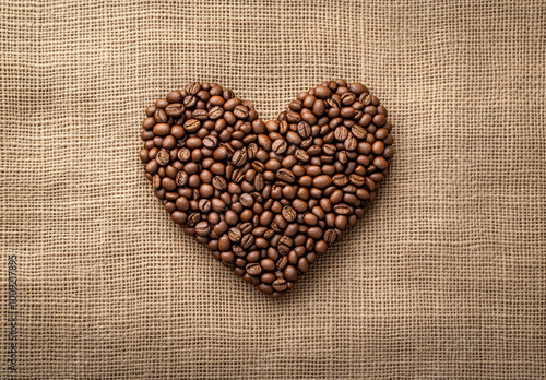 A heart-shaped arrangement made of coffee beans on a burlap background. 