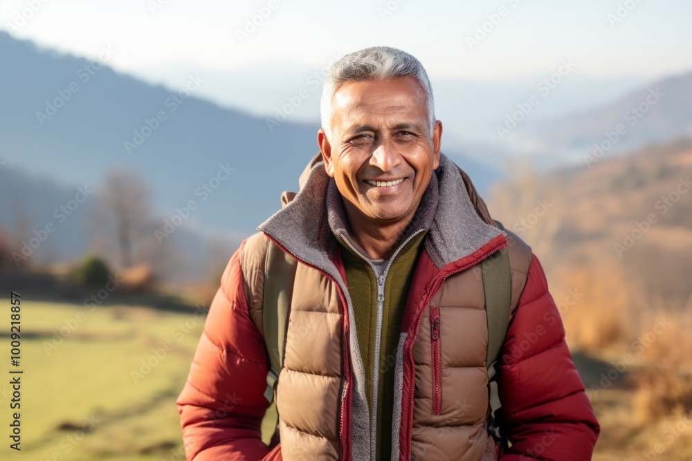 Portrait of a joyful indian man in his 60s donning a durable down jacket isolated in quiet countryside landscape Portrait of a joyful indian man in his 60s donning a durable down jacket isolated in quiet countryside landscape