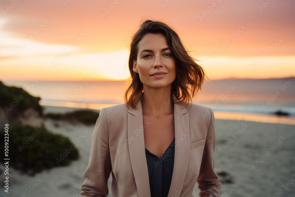 Portrait of a blissful woman in her 30s dressed in a stylish blazer in front of beautiful beach sunset Portrait of a blissful woman in her 30s dressed in a stylish blazer in front of beautiful beach sunset