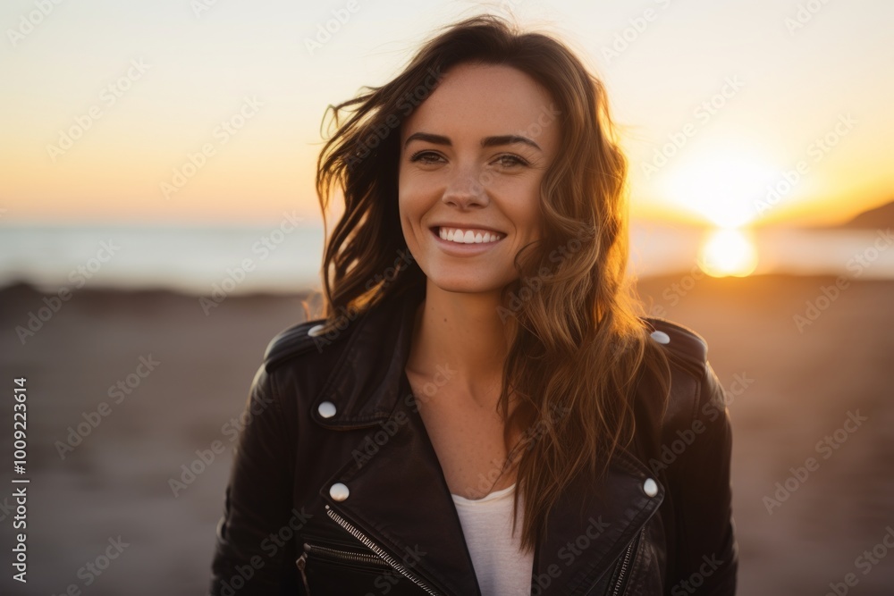 Portrait of a grinning woman in her 30s sporting a classic leather jacket isolated in beautiful beach sunset Portrait of a grinning woman in her 30s sporting a classic leather jacket isolated in beautiful beach sunset