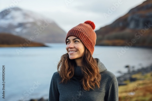 Portrait of a satisfied woman in her 40s donning a warm wool beanie in serene lakeside view