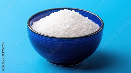 A blue bowl filled with white salt against a bright blue background.