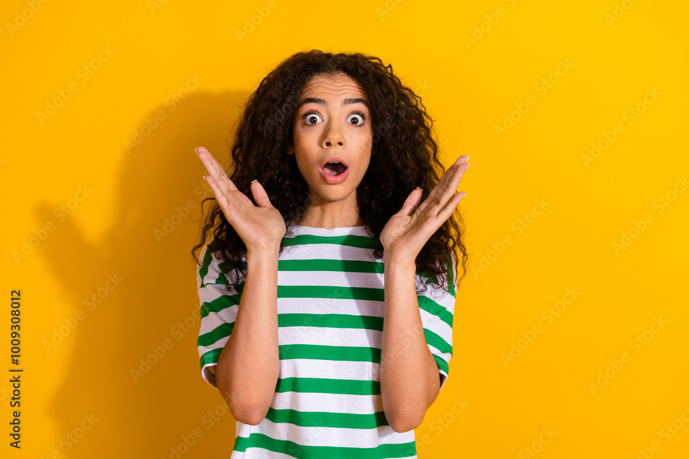 Portrait of pretty young girl raise arms open mouth wear striped t-shirt isolated on yellow color background Portrait of pretty young girl raise arms open mouth wear striped t-shirt isolated on yellow color background