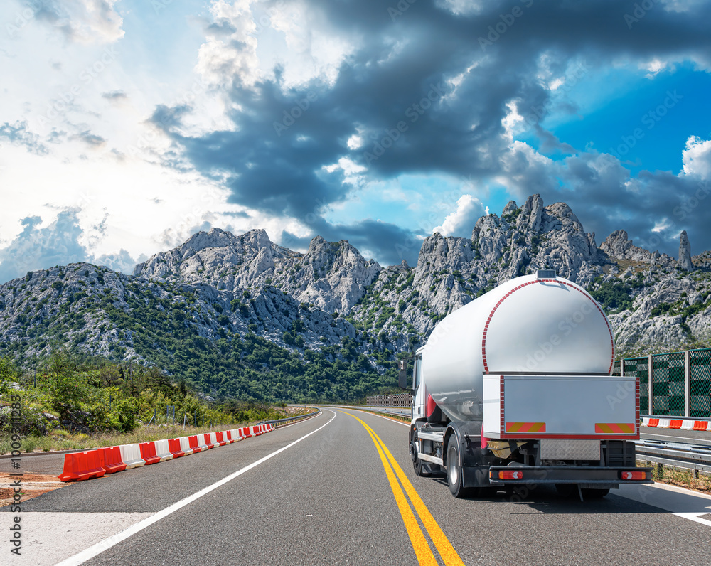 Fuel truck on a picturesque road. A silver tank truck transports fuel.