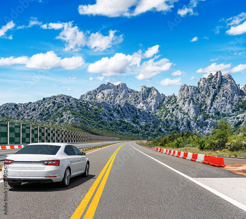 The car is driving along the highway surrounded by picturesque nature.