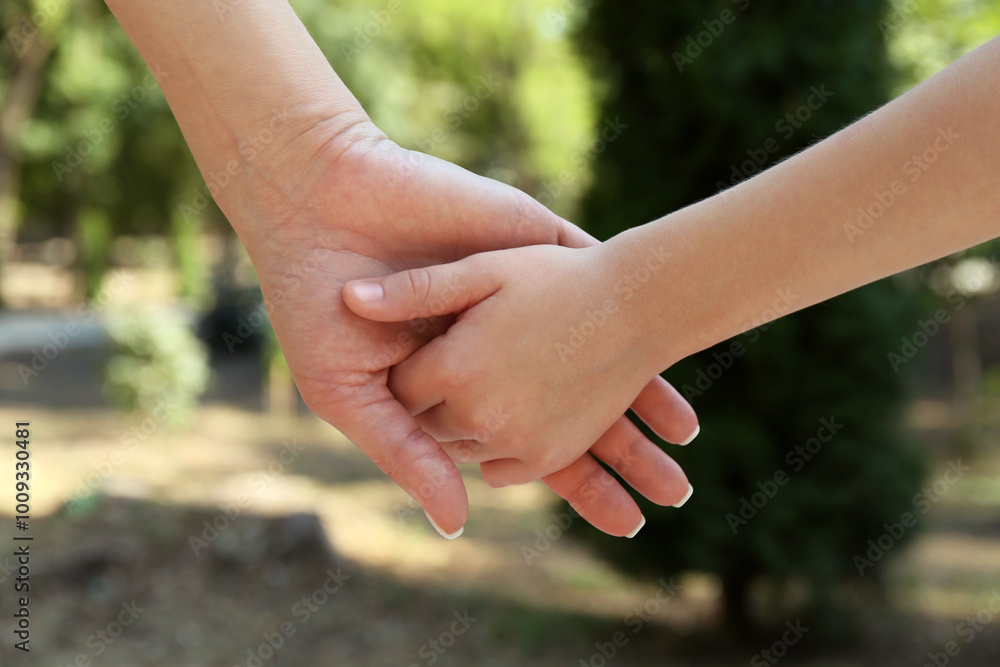 Mother and daughter holding hands in park, closeup