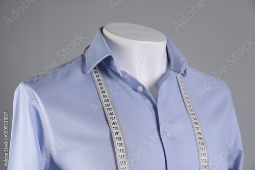 Male mannequin with light blue shirt and measuring tape on grey background, closeup