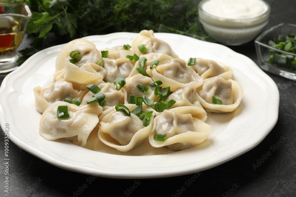 Delicious pelmeni with green onion on grey textured table, closeup Delicious pelmeni with green onion on grey textured table, closeup