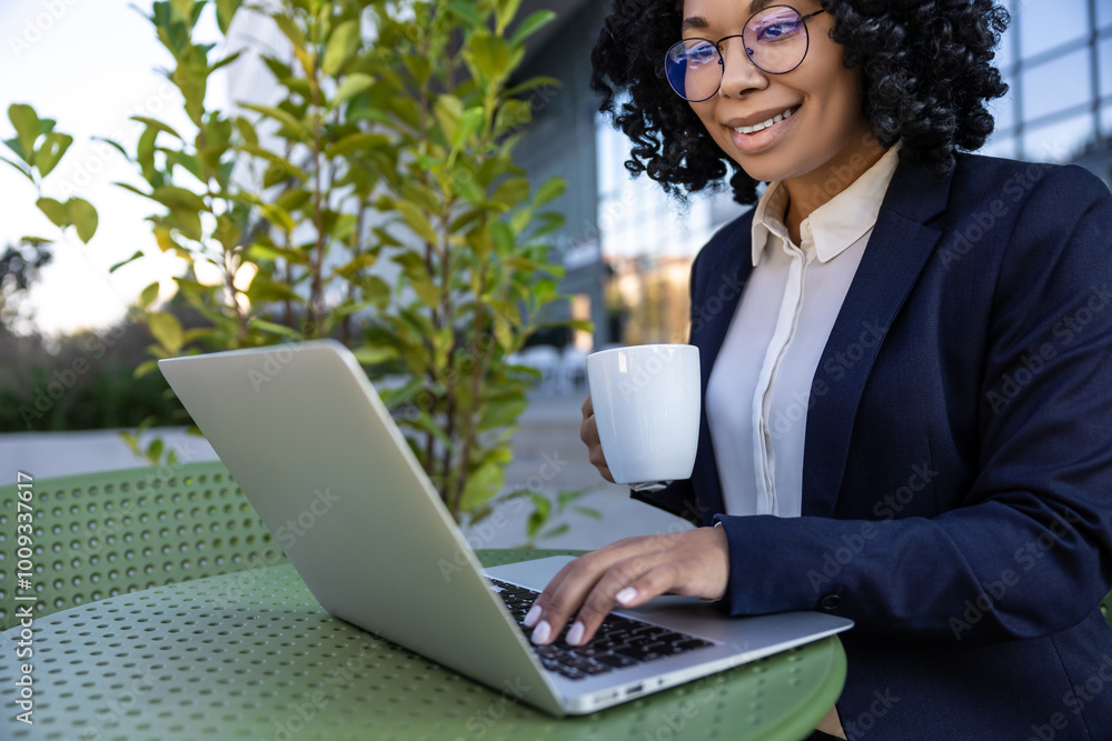 Business woman working on laptop and drinking coffee in a street cafe