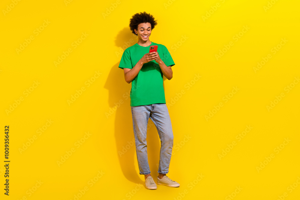 Full length photo of attractive funny guy wear green t-shirt texting instagram twitter telegram facebook emtpy space isolated yellow color background Full length photo of attractive funny guy wear green t-shirt texting instagram twitter telegram facebook emtpy space isolated yellow color background