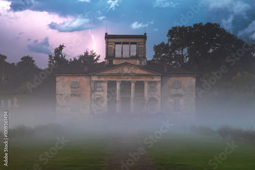 A majestic 19th-century villa sits amid autumn fog, with a historic garden and a long driveway leading toward it.