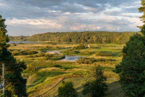 A serene landscape at dusk with a river and rolling greenery