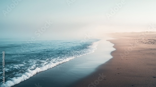 A serene beach scene showing gentle waves lapping at a sandy shore under a misty sky, perfect for relaxation and tranquility.