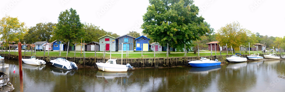 Obraz premium In Biganos, a charming village in the Arcachon basin, in Gironde (New Aquitaine), the cabins were built on the fishing port and painted in multiple colors. Today it is a pleasant little marina